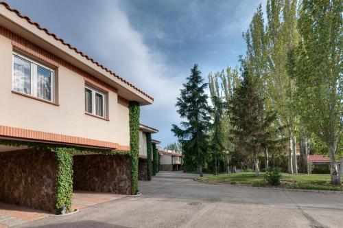 a road in front of a building with trees at Gran Hotel Los Angeles in Getafe