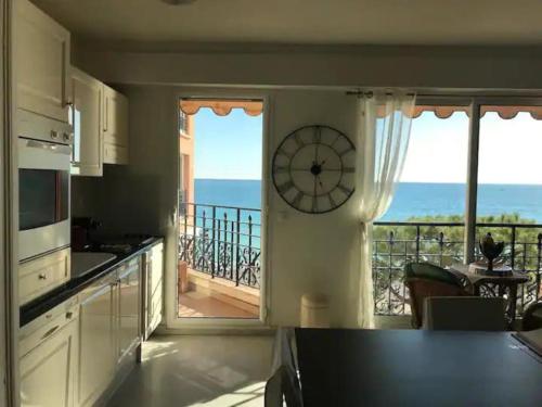 een keuken met een klok aan de muur en een balkon bij Victoria bilocale centro città e vista mare in Menton
