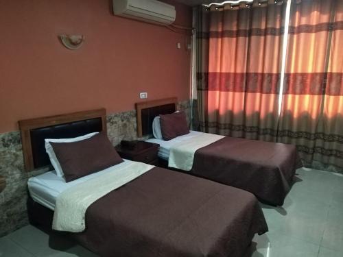 a hotel room with two beds and a window at Amman Palace Hotel in Amman