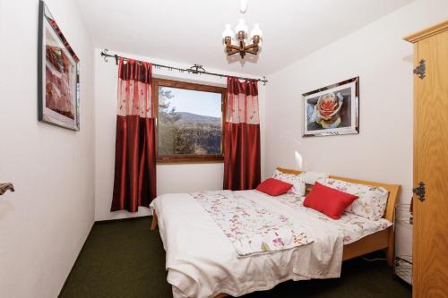 a bedroom with a bed with red curtains and a window at Ferienhaus Hölzl 