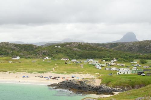 a group of houses on a hill next to a beach at Achmelvich Beach Youth Hostel in Achmelvich