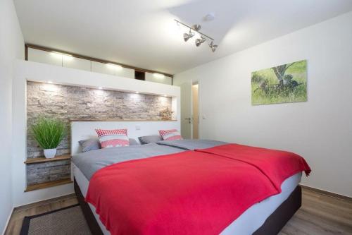 ein Schlafzimmer mit einem roten Bett und einer Ziegelwand in der Unterkunft Glückspilz in Obermaiselstein