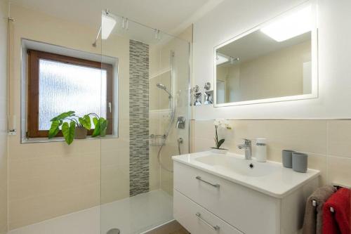 ein Bad mit einem Waschbecken, einer Dusche und einem Spiegel in der Unterkunft Glückspilz in Obermaiselstein