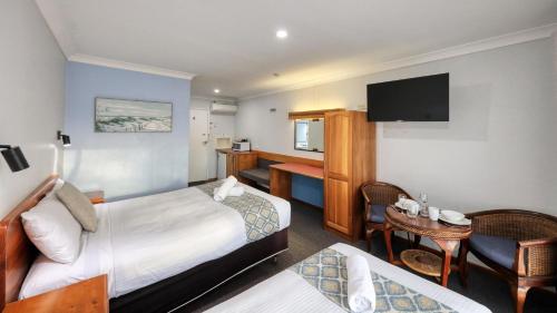 a hotel room with a bedroom with a bed and a desk at Kempsey Powerhouse Motel in Kempsey