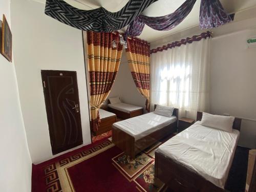 um pequeno quarto com 2 camas e uma janela em MIRONSHOX GuEST HOUSE em Khiva