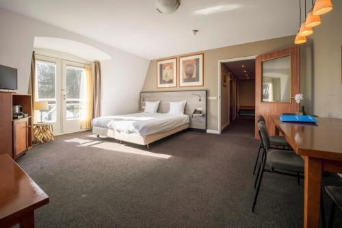 Cette chambre comprend un lit et un bureau. dans l'établissement Fletcher Hotel Restaurant De Witte Raaf, à Noordwijk