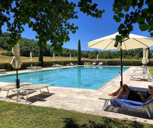 サン・ジミニャーノにあるI Girasoli San Gimignano Apartmentsのカップルがスイミングプールの隣の椅子に座って座っている