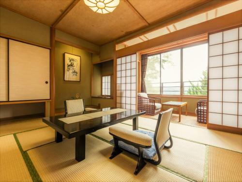 Zimmer mit einem Tisch, Stühlen und einem Fenster in der Unterkunft Kurofune Hotel in Shimoda