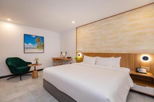 a hotel room with a large bed and a green chair at Petro House Vung Tau - Block A in Vung Tau