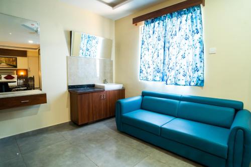 a living room with a blue couch and a window at Safa Residency in Tiruchchirāppalli
