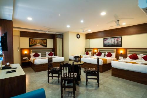a hotel room with two beds and a table and chairs at Safa Residency in Tiruchchirāppalli