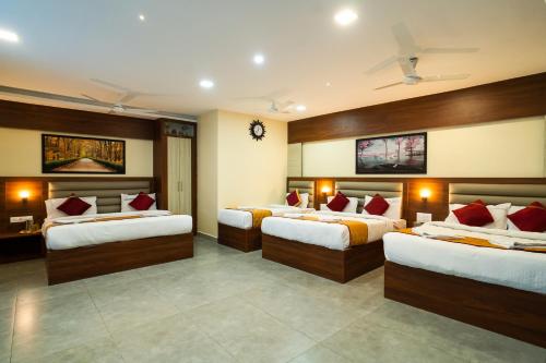 a hotel room with three beds with red pillows at Safa Residency in Tiruchchirāppalli