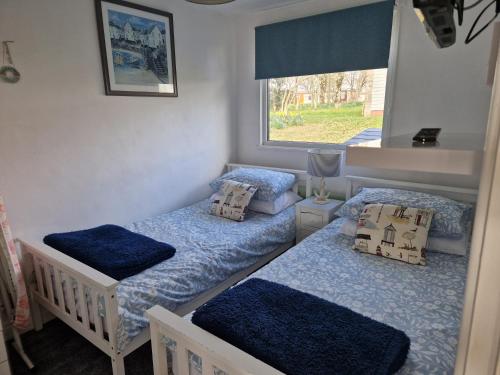 two twin beds in a room with a window at Caldon Holiday Chalet sleeps 4 in Dartmouth WIFI Electric inc Pet friendly in Dartmouth