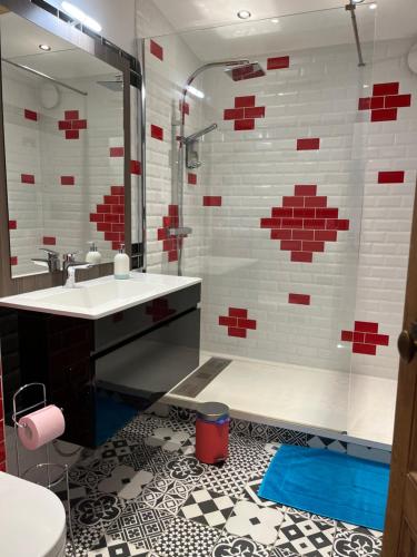 a bathroom with a sink and a shower with red and white tiles at Le P’tit Bois Doré in Blanquefort