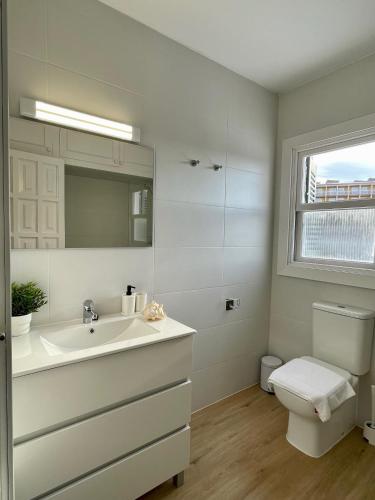 a bathroom with a sink and a toilet and a window at BINIFORCAT in Cala en Forcat
