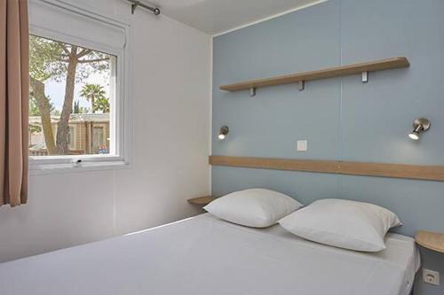 a bedroom with a bed with two pillows and a window at La petite Camargue in Le Grau-du-Roi