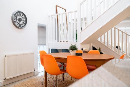 a dining room with a wooden table and orange chairs at The Amazing Triplex in Sheffield