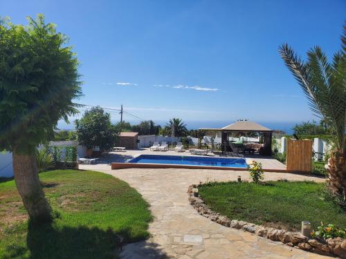 a backyard with a swimming pool and a palm tree at Casa Granero in Frigiliana