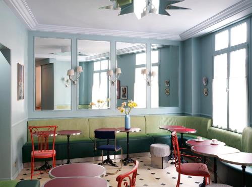 ein Restaurant mit Tischen, Stühlen und Fenstern in der Unterkunft Hôtel Beauregard in Paris