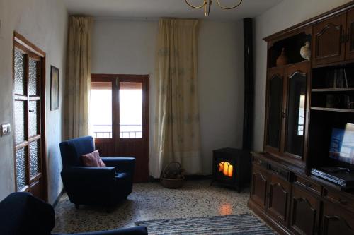 a living room with a tv and a chair at Casa Estrella de las nieves La Alpujarra in Bérchules