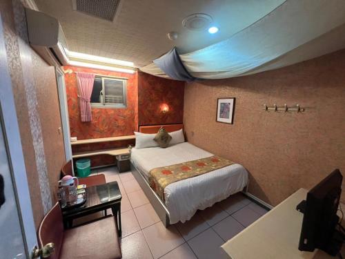a bedroom with a bed and a table in a room at Boston Hotel in Chiayi City