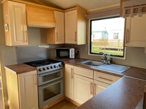 a kitchen with a stove and a sink and a window at R&S HOLIDAY HOMES THE CHASE r14 in Skegness