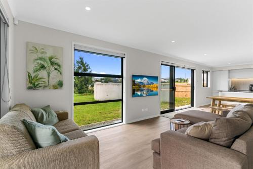 ein Wohnzimmer mit zwei Sofas und einem Tisch in der Unterkunft Sweet and Stylish - Mangawhai Heads Holiday Home in Mangawhai
