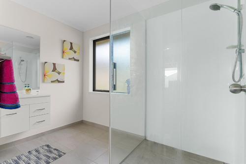 a white bathroom with a glass shower stall at Summertime Bliss - Mangawhai Heads Holiday Home in Mangawhai