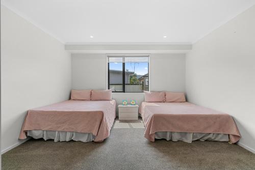 two beds in a room with white walls and a window at Summertime Bliss - Mangawhai Heads Holiday Home in Mangawhai