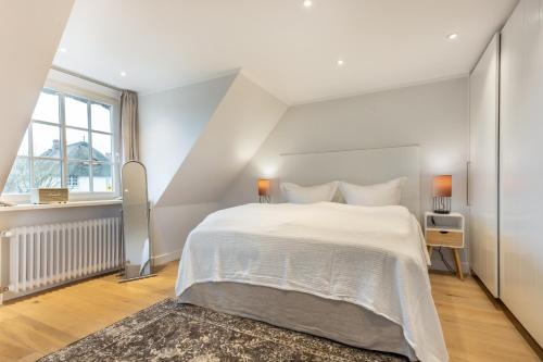 a white bedroom with a large bed and a window at Ferienhaus Essex in Keitum