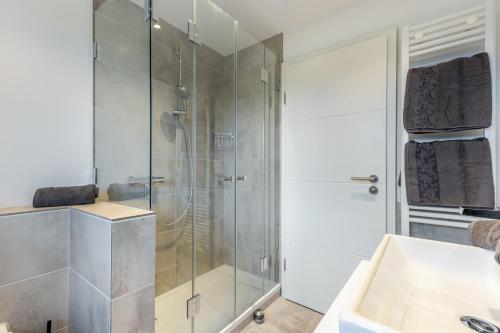 a bathroom with a glass shower and a sink at Ferienhaus Essex in Keitum