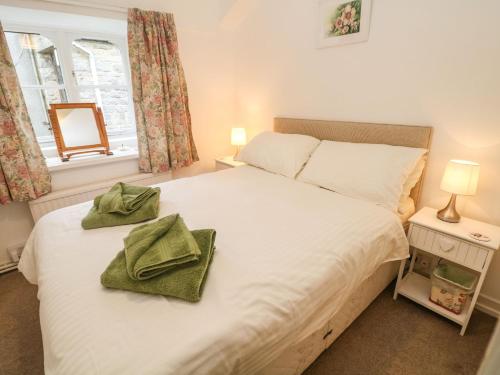 a bedroom with a white bed with two green towels on it at Sycamore Cottage in Hucklow
