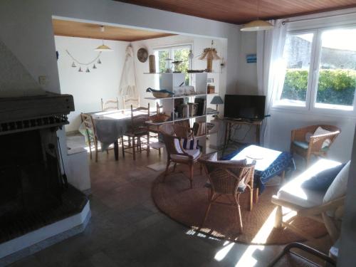 - un salon avec une cheminée, une table et des chaises dans l'établissement Maison oléronaise avec la plage à pied et la piste cyclable au bout du jardin, à Dolus-d'Oléron