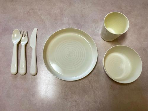 a table with two white plates and a fork and knife at Kokoyui Guest House in Nachikatsuura