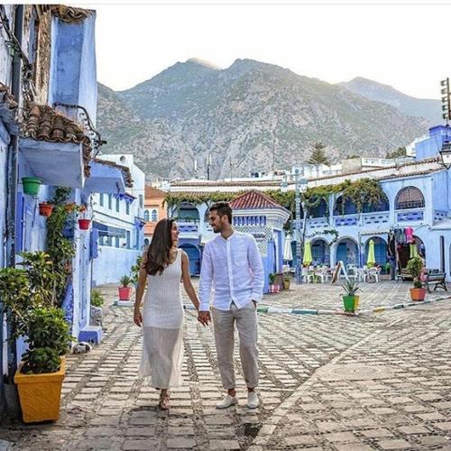 a man and a woman walking down a street at DAR Casa Plasa Grande CHEFCHAOUEN in Chefchaouene
