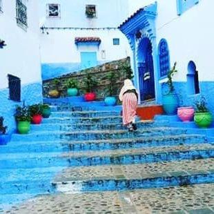 a woman walking down the stairs of a building at DAR Casa Plasa Grande CHEFCHAOUEN in Chefchaouene