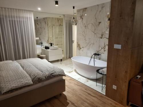 バンスカー・ビストリツァにあるKrásný apartman s vybavením a bezplatným parkovanimのベッドルーム(バスタブ付)、広いバスルームが備わります。