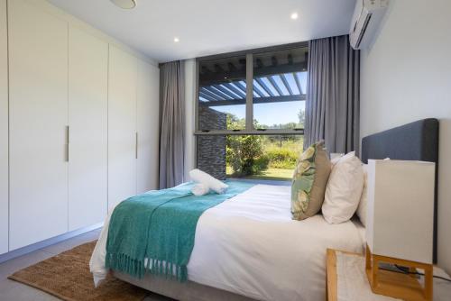 a bedroom with a bed and a large window at Modern Garden Unit in Pebble Beach in Umhlanga