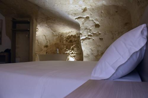 a white pillow sitting on a bed in a room at 5 Elementi Sassi Matera in Matera