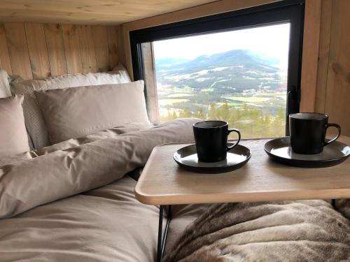 two coffee cups on a table in a room with a window at Baugsberget Fjelltopphytter in Alvdal