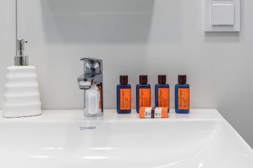 a bathroom sink with four bottles of essential oils on it at Modern Shellter Apartment Beachside Rogowo by Renters in Rogowo
