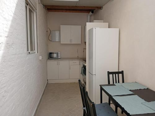 Rooms Burjassot في برجست: مطبخ مع طاولة وثلاجة بيضاء