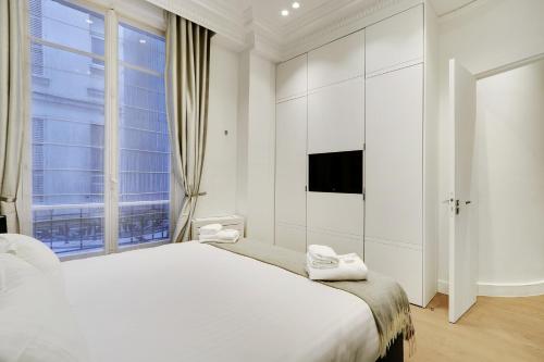 ein weißes Schlafzimmer mit einem großen Bett und einem Fenster in der Unterkunft Pick A Flat's Apartment in Triangle d'Or - Pierre 1er de Serbie in Paris