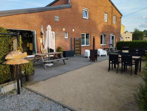a patio with tables and chairs and a building at DE SMISHOEVE met kinderpret, dieren en wellness in Heers