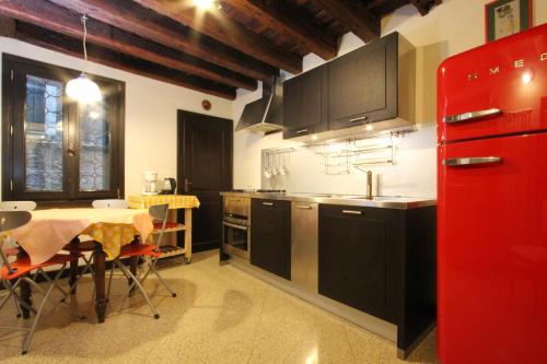 a kitchen with a table and a red refrigerator at City Apartments Biennale in Venice