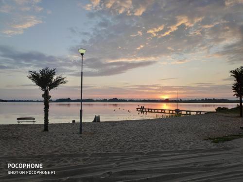 a beach with a palm tree and a light pole at Hotel Marina in Nielisz