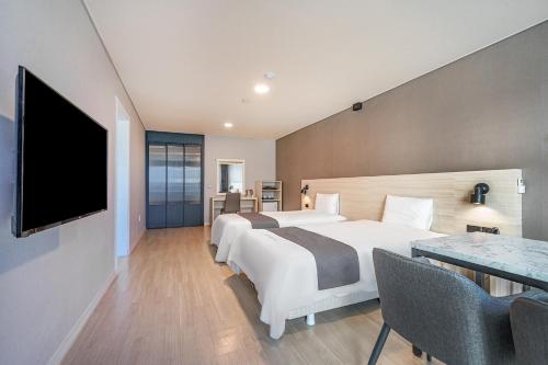 a hotel room with two beds and a flat screen tv at Gyeongpo Soo Hotel in Gangneung