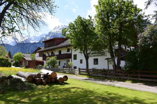 a pile of logs in the grass in front of a house at Haus Alpenblume in Ehrwald