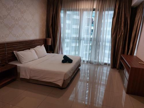 KLCC Regalia Suites Infinity Pool Kuala Lumpur في كوالالمبور: غرفة نوم مع سرير مع قبعة سوداء عليه