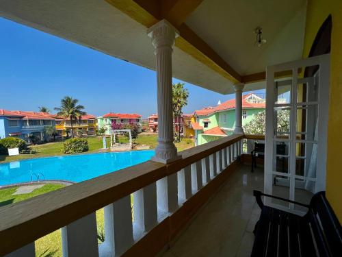 balcón con vistas a la piscina en Villa Marina By The Beach Goa, en Benaulim